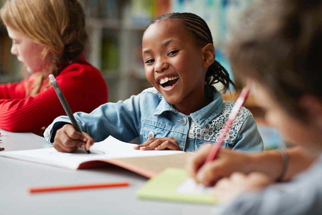 Student smiling while writing in a classroom